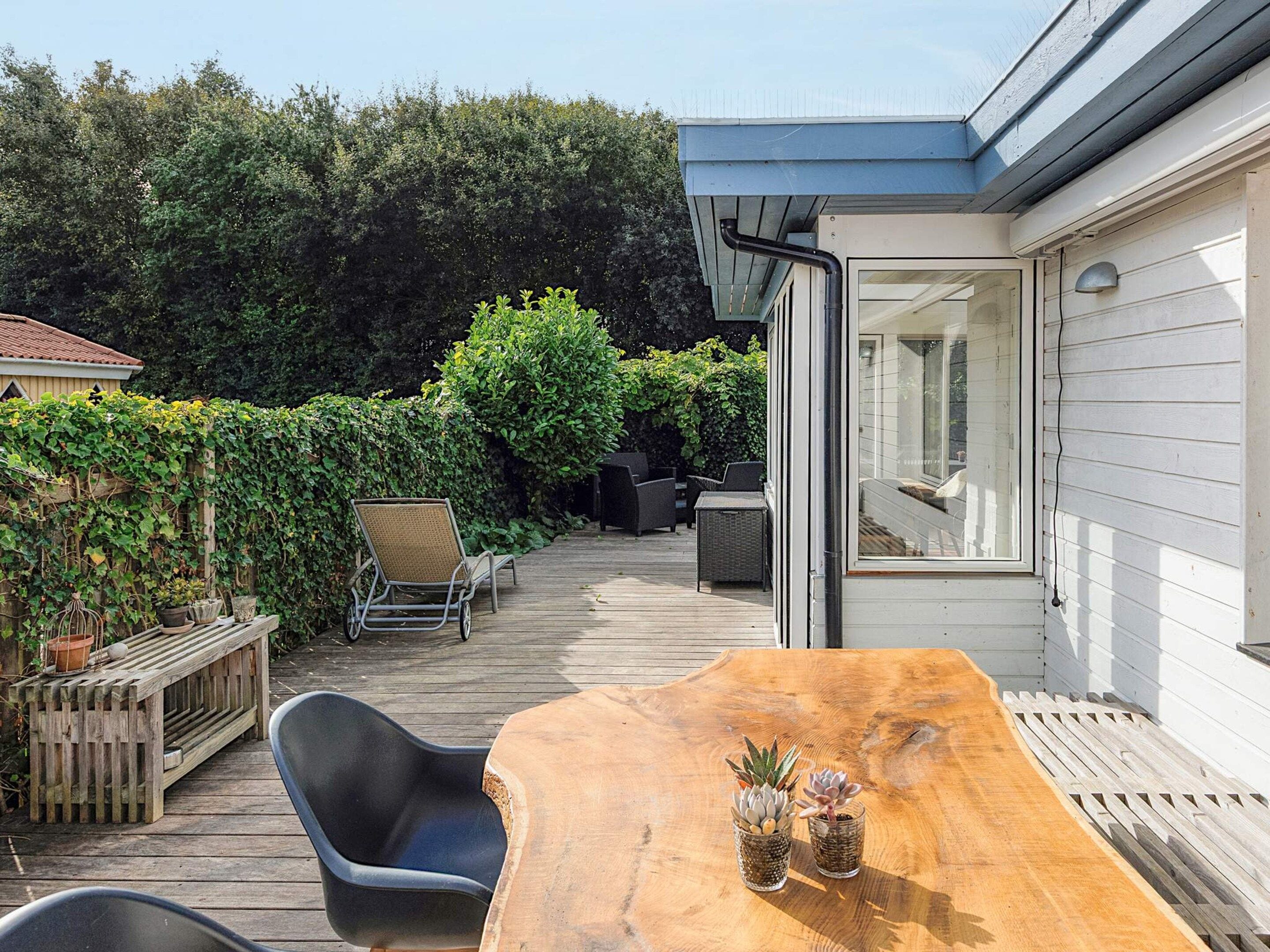 A wooden deck with outdoor furniture, a table, and potted plants.