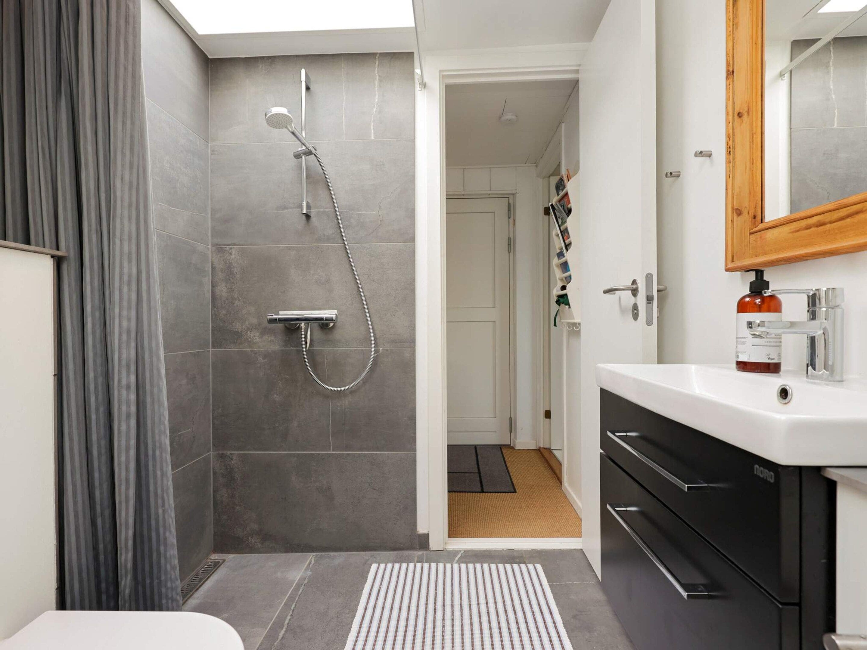 Ein modernes Badezimmer mit Dusche, Waschbecken und Spiegel.