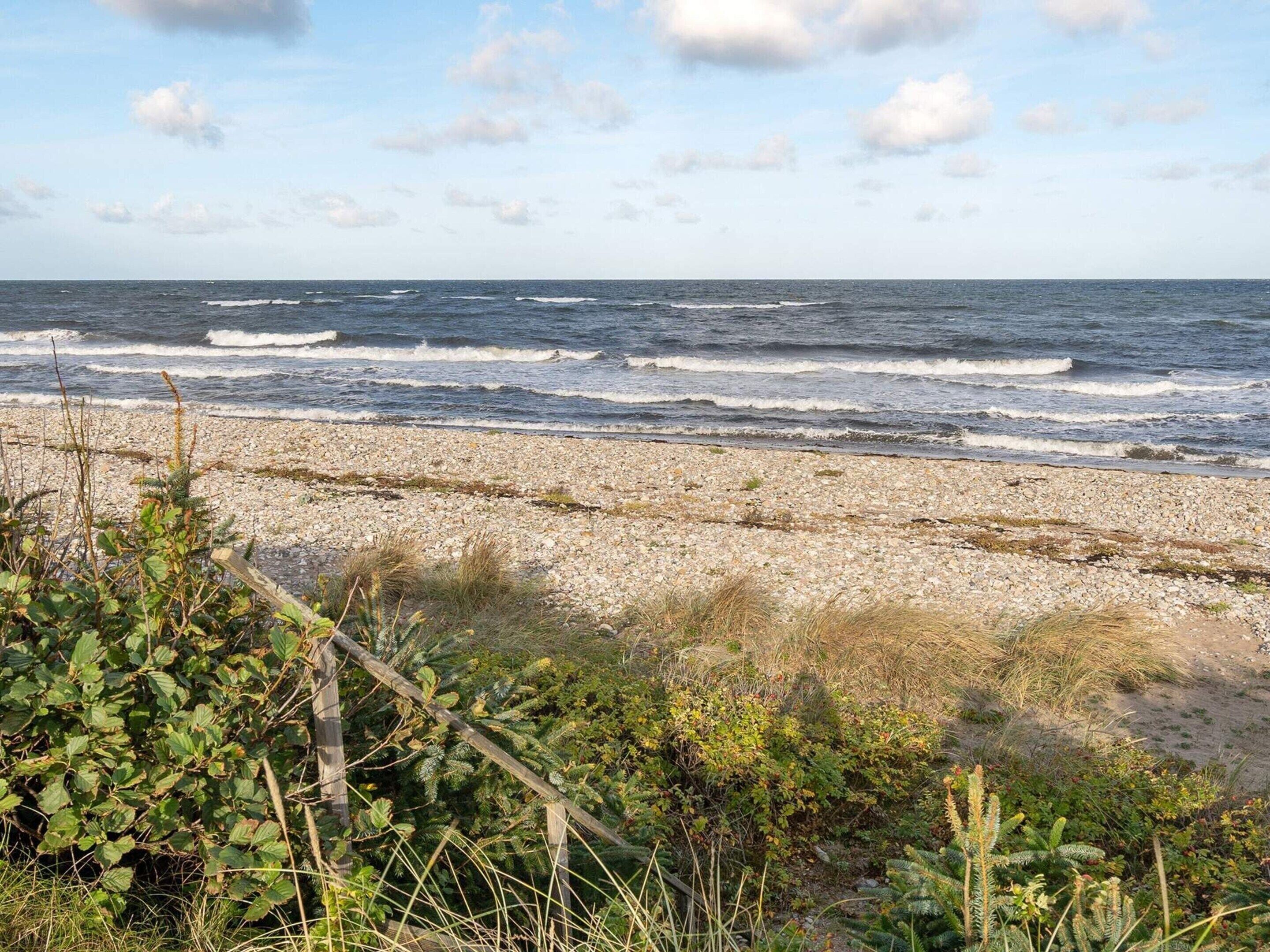 A rocky beach with waves crashing onto the shore and a clear sky.