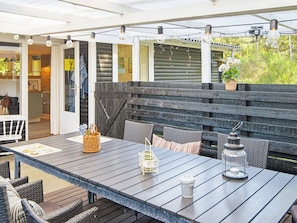 An outdoor patio with a wooden table, wicker chairs, and a lantern. - 4 Person Holiday Home in Glesborg (Glesborg)