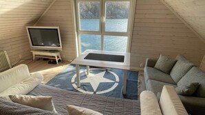 A cozy loft bedroom with a large window overlooking a body of water, a television, and a small table. - 6 Person Holiday Home in Rubbestadneset (Bomlo)