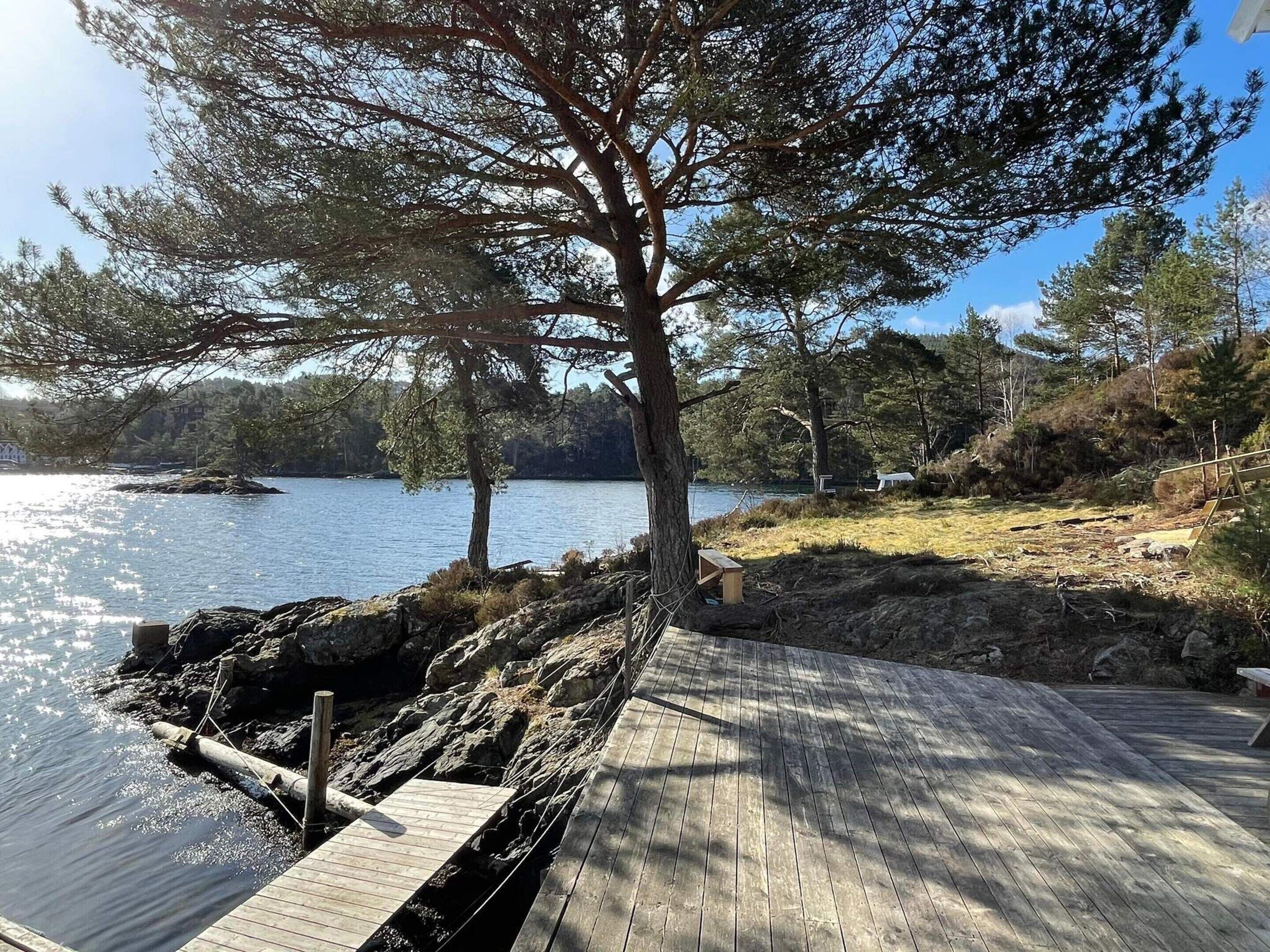 A wooden dock extending into a calm lake, surrounded by trees and rocky terrain.