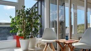 Een moderne kamer met een groot raam, een potplant, twee witte stoelen, een houten tafel en een witte badkuip.