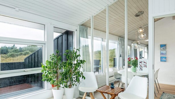 Een moderne badkamer met een badkuip, witte stoelen en potplanten.