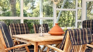 A wooden table with striped chairs, a terracotta pot, and a glass dome. - Holiday Home Near Kampinge Beach (Hollviken)