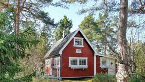 A red wooden cabin with a gabled roof, surrounded by dense forest. - Holiday Home Near Kampinge Beach (Hollviken)