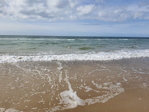A beach with waves, a clear sky, and a distant shoreline.