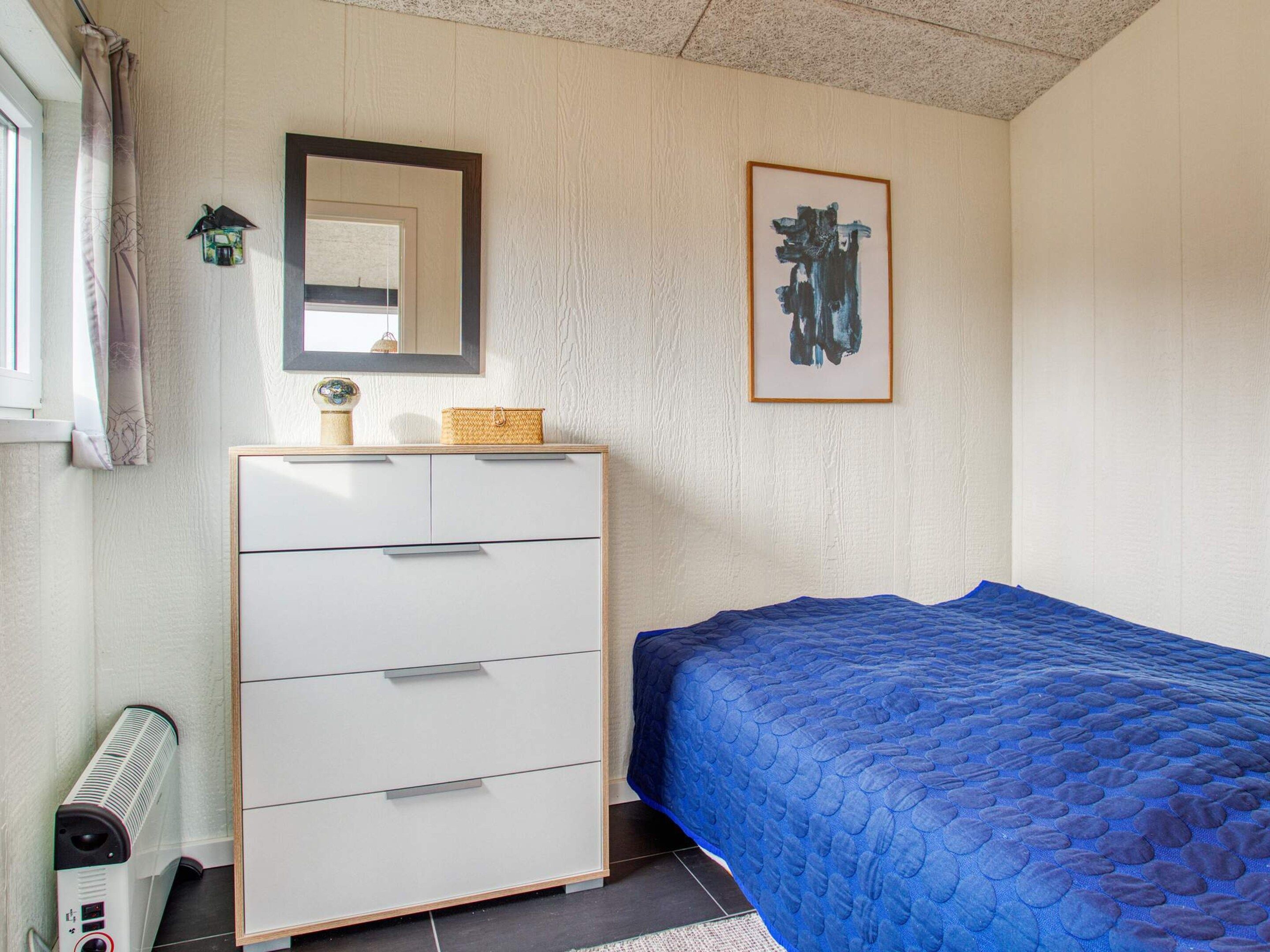 A bedroom with a bed, a dresser, a mirror, and a framed picture on the wall.