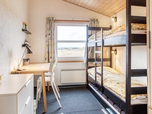 Une chambre avec des lits superposés, un bureau, une chaise et une fenêtre donnant sur un beau paysage.
