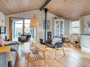 A spacious living room with a fireplace, wooden flooring, and a large window offering a view.