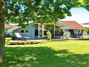 A house with a covered patio, outdoor furniture, and a lawn. - Tranquil Oasis in Blavand-by Traum (Rudkobing)