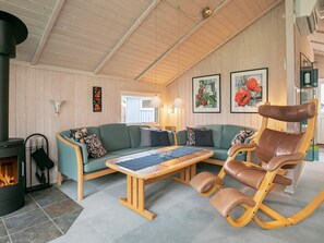 A cozy living room with a green sofa, a wooden coffee table, and a brown leather chair. - Tranquil Oasis in Blavand-by Traum (Rudkobing)