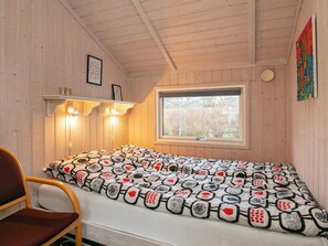 A small, cozy room with a single bed, a chair, a window, and wooden walls. - Tranquil Oasis in Blavand-by Traum (Rudkobing)