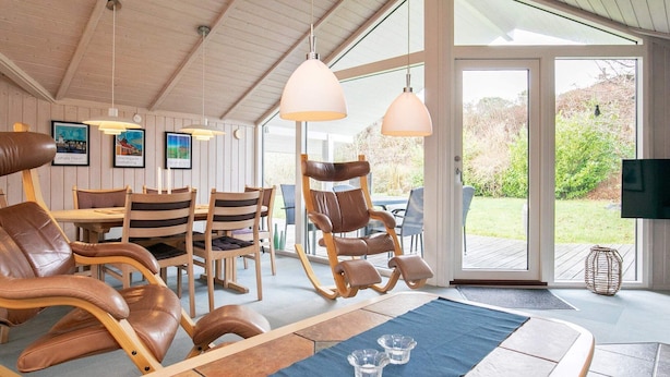 A cozy room with wooden furniture, a dining area, and a view of the outdoors. - Tranquil Oasis in Blavand-by Traum (Rudkobing)