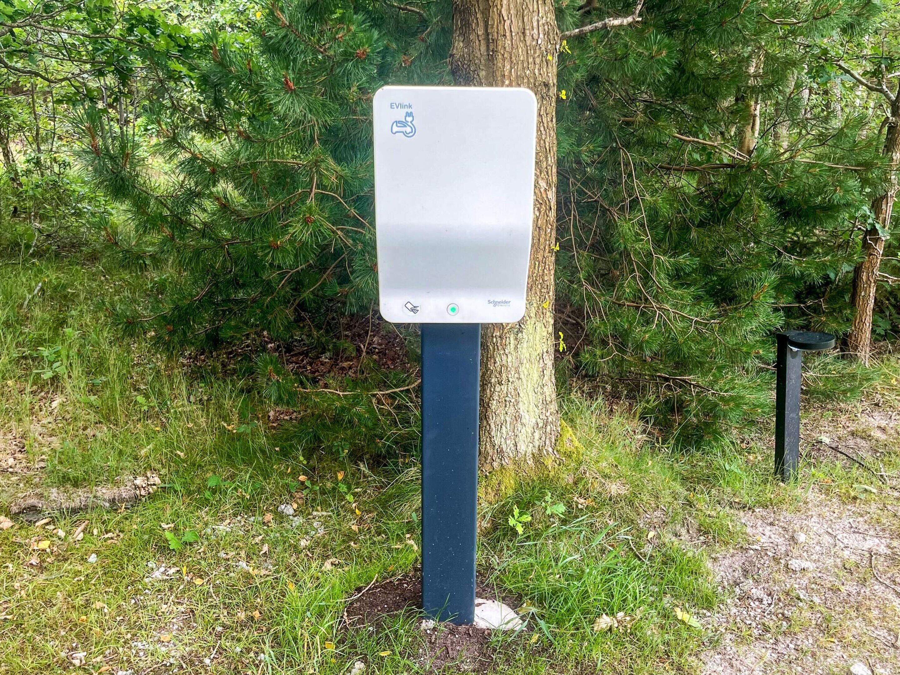 A portable EVLink charging station in a forested area.