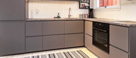A modern kitchen with grey cabinets, a built-in oven, and a window with a view.