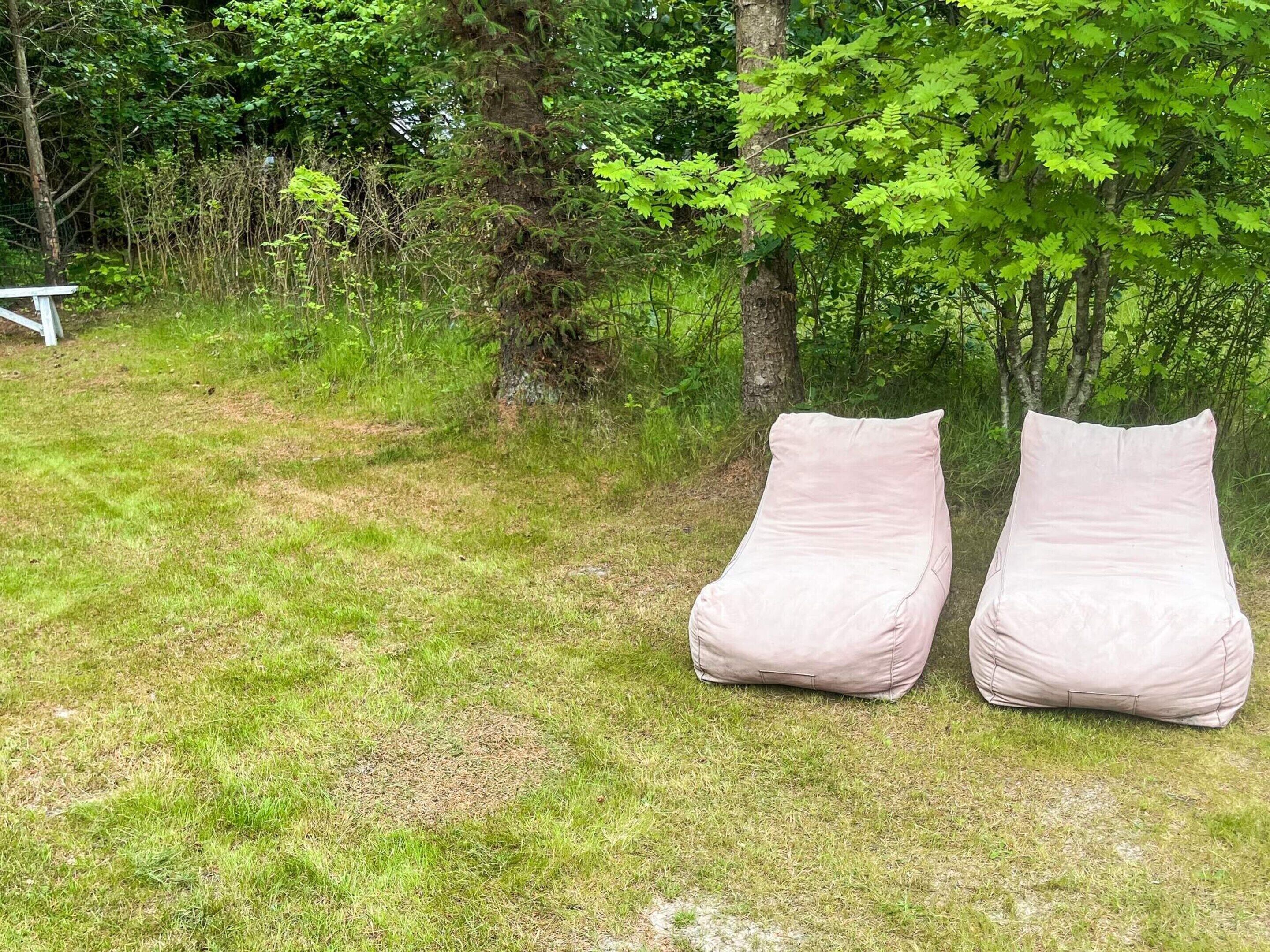 Two outdoor bean bags in a grassy area with trees in the background.