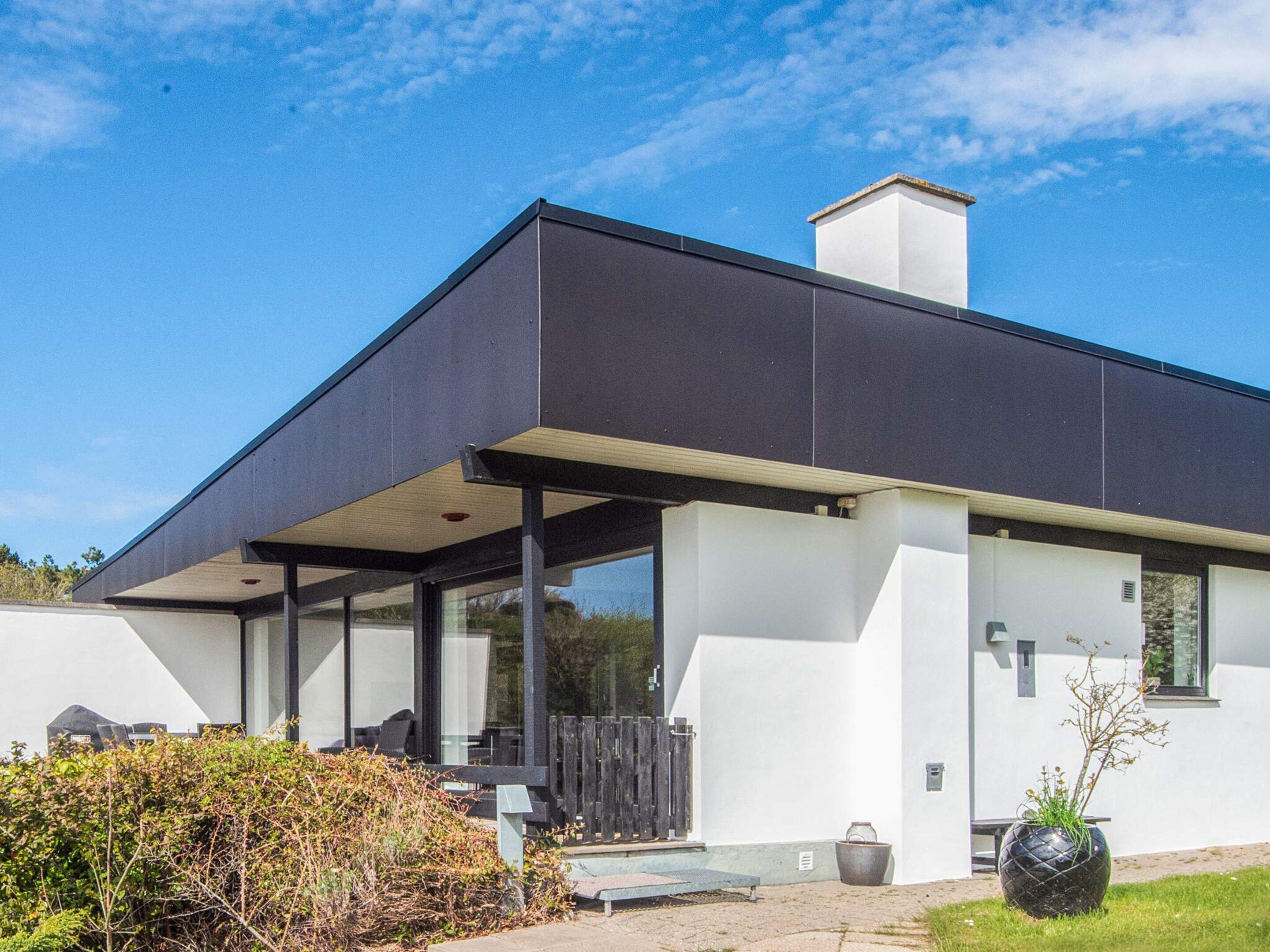 A modern house with a flat roof, large windows, and a covered patio area.
