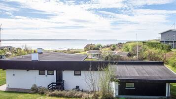 A modern house with a flat roof, a small porch, and a view of the sea.