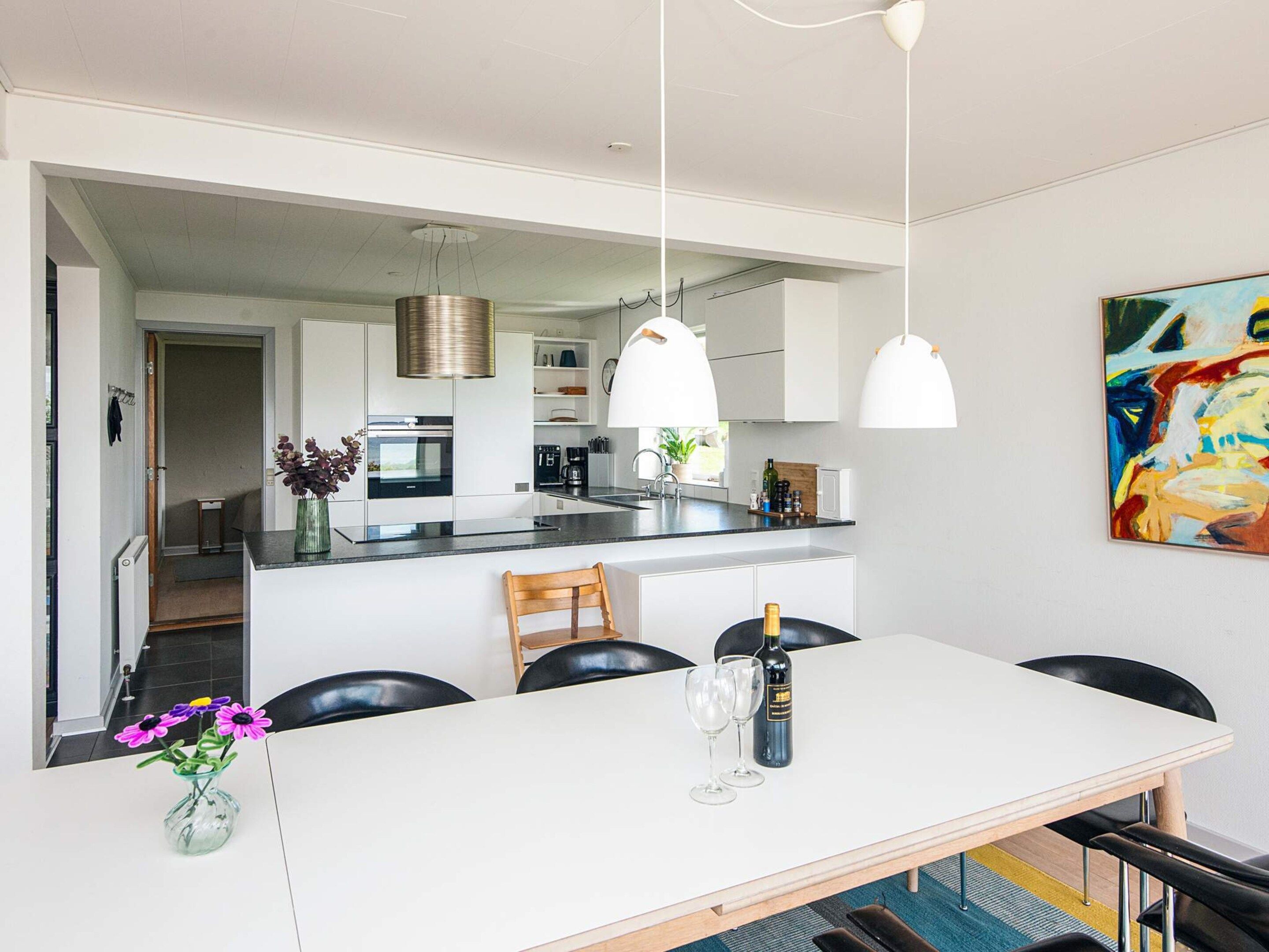 A modern kitchen with white cabinets, a central island, and pendant lighting.