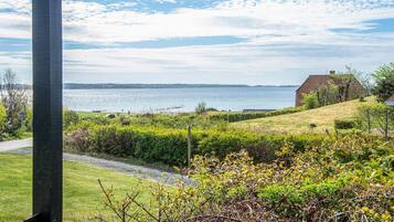 A coastal landscape with a grassy area, a pathway, and a distant view of the sea.