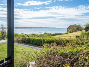 A coastal landscape with a grassy area, a pathway, and a distant view of the sea.