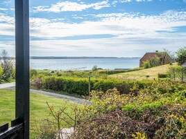 A coastal landscape with a grassy area, a pathway, and a distant view of the sea.