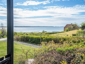 A coastal landscape with a grassy area, a pathway, and a distant view of the sea.