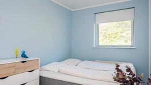 A bedroom with a bed, a dresser, a window with a view of greenery, and a small plant on the dresser. - 5 Star Holiday Home in Ebeltoft (Ebeltoft)