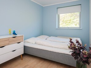 A bedroom with a bed, a dresser, a window with a view of greenery, and a small plant on the dresser. - 5 Star Holiday Home in Ebeltoft (Ebeltoft)
