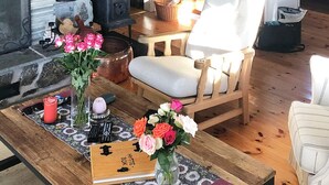 A wooden table with a book, vases with flowers, and a remote control. - 8 Person Holiday Home in Etnedal-by Traum (Etnedal)