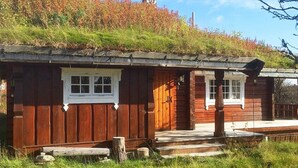 A rustic wooden cabin with a thatched roof, a porch, and a small window. - 8 Person Holiday Home in Etnedal-by Traum (Etnedal)