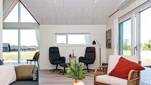 A modern living room with a sofa, two armchairs, a coffee table, and a large window offering a view of the outdoors. - 4 Star Holiday Home in Ansager (Ansager)