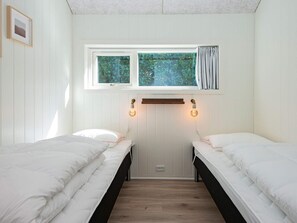 Quarto com duas camas, janela com cortinas e luminárias fixadas na parede.