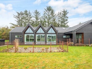 A modern house with a large glass window and a fenced garden. - 4 Star Holiday Home in Ansager (Ansager)