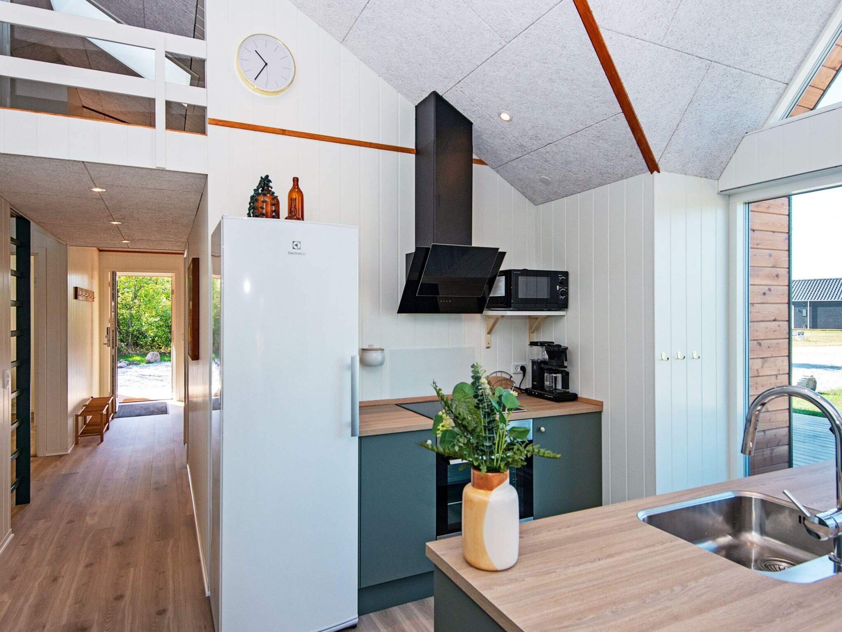 Una cocina moderna con microondas integrado, cafetera y una planta en la encimera.