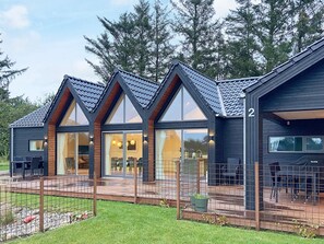 Une maison moderne à deux étages, dotée d’une terrasse, de grandes fenêtres et d’une enseigne portant le chiffre « 2 ».
