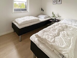A bedroom with two single beds, a bedside table with a lamp, and a window. - 6 Person Holiday Home in Saltum (Saltum)