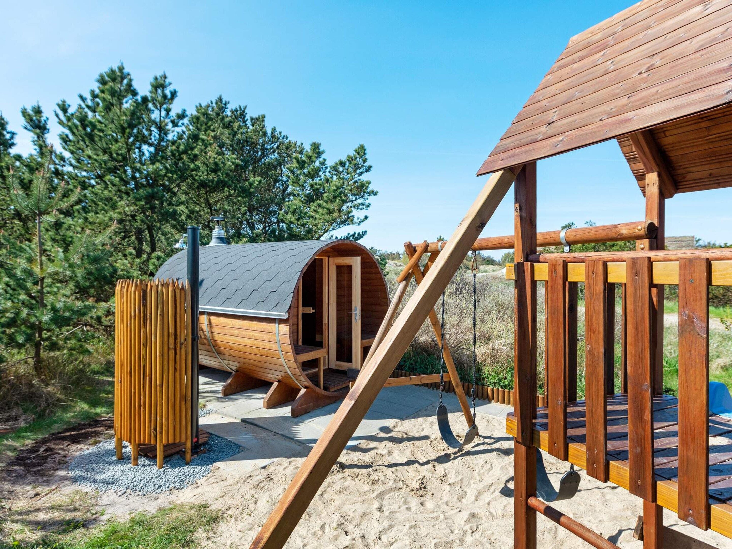 A wooden play structure with a slide and a swing set.