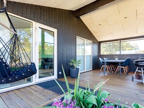 A modern outdoor patio with a hammock, a dining area, and a grill.