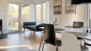 A modern interior with a sofa, dining table, chairs, and a fireplace. - 6 Person Holiday Home in Saltum (Saltum)