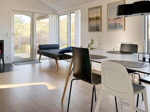 A modern interior with a sofa, dining table, chairs, and a fireplace. - 6 Person Holiday Home in Saltum (Saltum)
