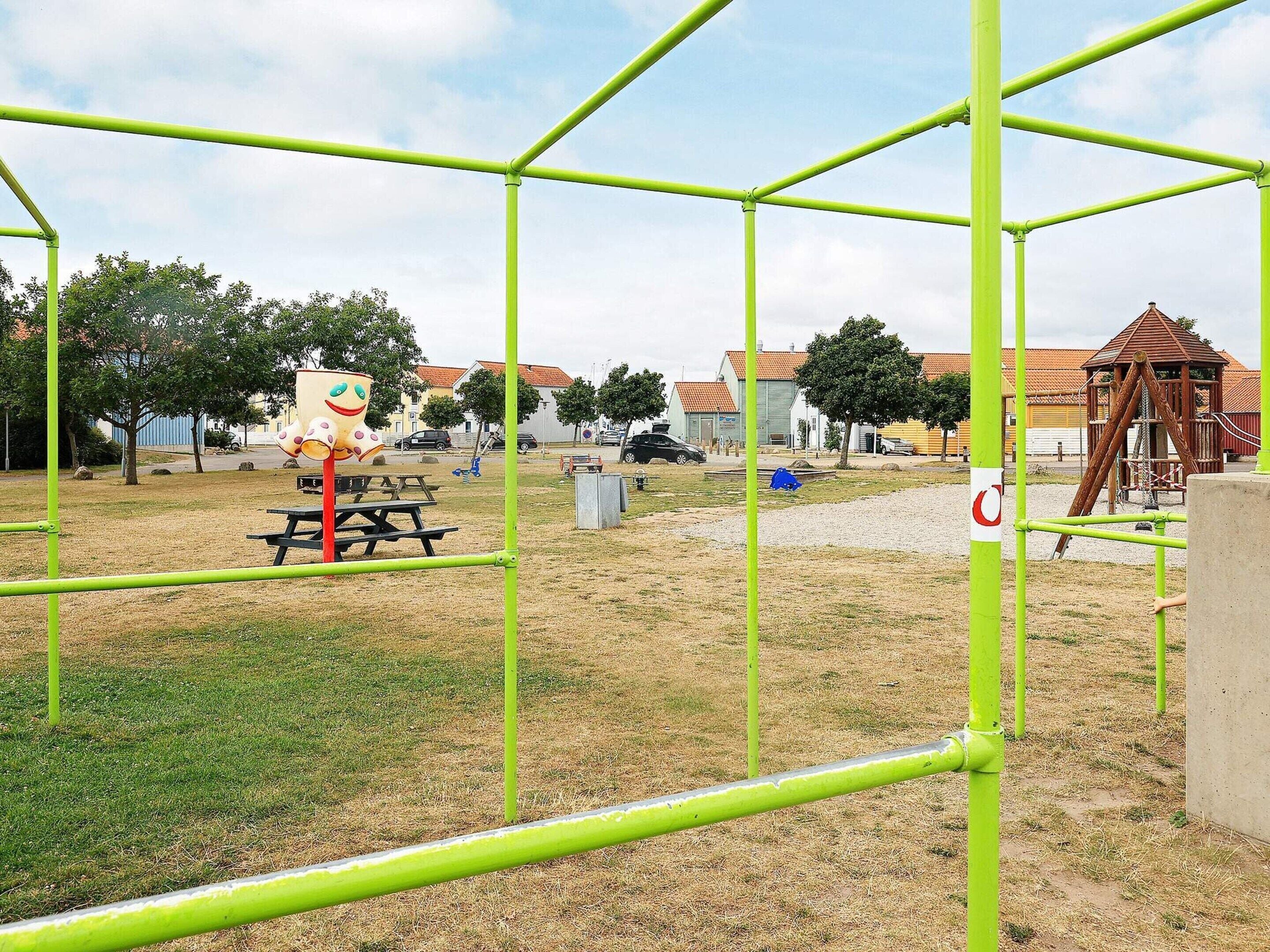 A playground with green metal frames, a picnic table, and a play structure.