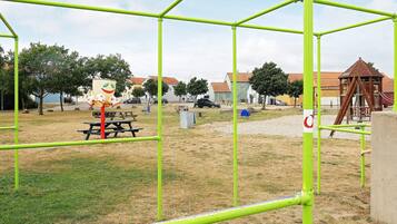 A playground with green metal frames, a picnic table, and a play structure.