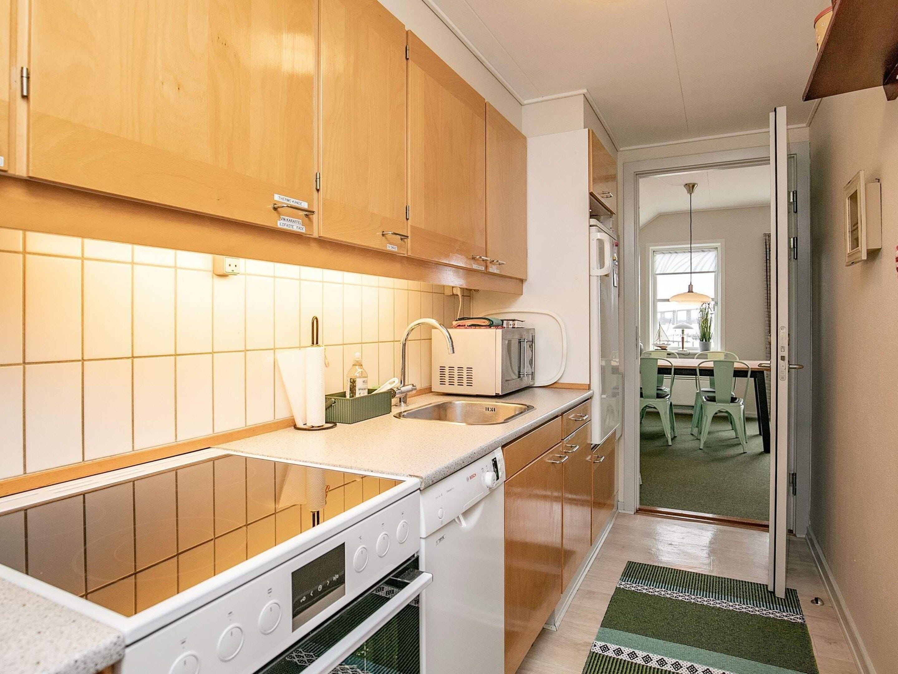 A kitchen with wooden cabinets, a built-in oven, a microwave, and a sink.