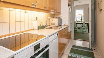 A kitchen with wooden cabinets, a built-in oven, a microwave, and a sink.