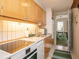 Una cocina con armarios de madera, horno empotrado, microondas y fregadero.