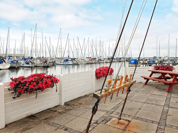 A marina with boats docked, a wooden bench, and red flowers.