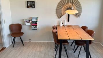 Zona pranzo con tavolo in legno, quattro sedie, lampadario e libreria a parete.
