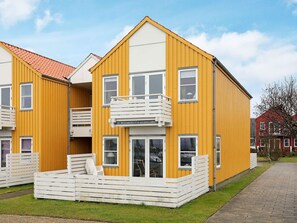 A yellow building with a balcony and a small outdoor seating area.